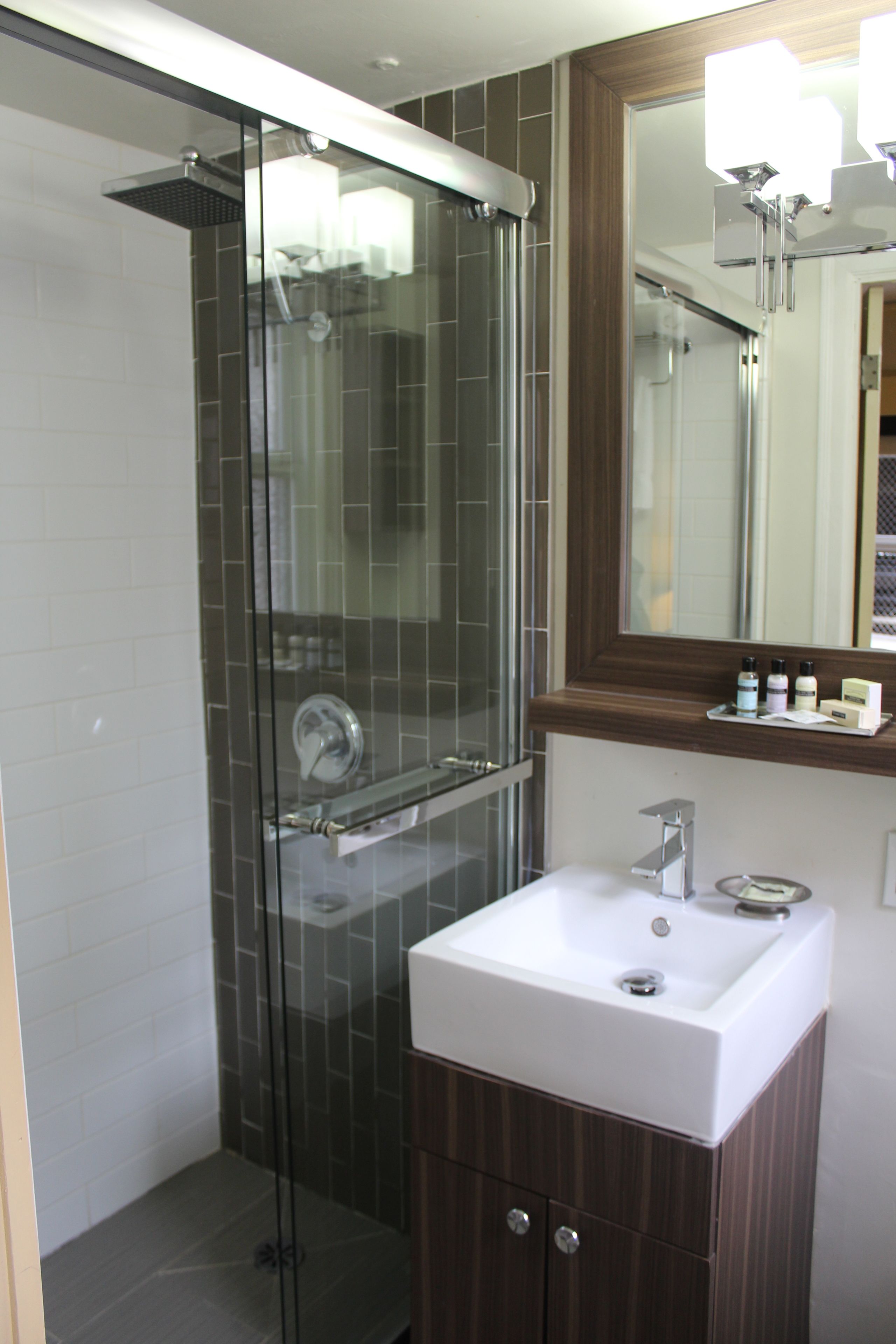 A modern bathroom with a glass-enclosed shower, a white sink, and a wooden vanity.