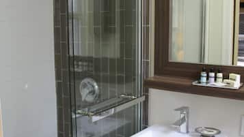 A modern bathroom with a glass-enclosed shower, a white sink, and a wooden vanity.