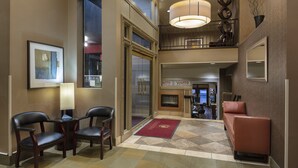 A hotel lobby with a check-in desk, seating area, and a fireplace.