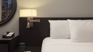A hotel room with a bed, a nightstand, a lamp, a phone, and a digital clock.