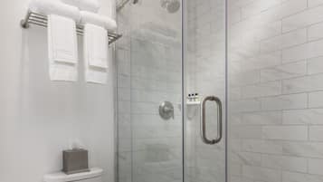 Une salle de bain moderne avec une douche à parois de verre, des toilettes et un sol carrelé de couleur blanche.