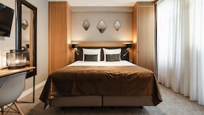 A hotel room with a large bed, a desk with a chair, a TV, and a window with curtains. - The Delphi - Amsterdam Townhouse (Amsterdam)