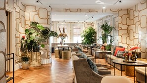 A spacious hotel lobby with a modern design, featuring a long sofa, multiple seating areas, and a variety of plants. - The Delphi - Amsterdam Townhouse (Amsterdam)