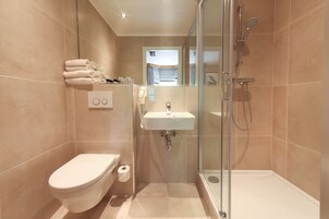 Ein modernes Badezimmer mit Toilette, Waschbecken und einer Duschkabine.