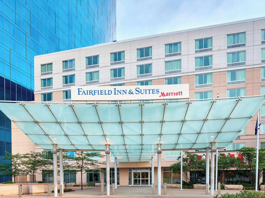 L’entrée d’un hôtel Marriott Fairfield Inn & Suites, avec une passerelle couverte et un bâtiment à la façade de verre en arrière-plan.