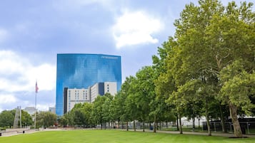 Ein JW Marriott Hotel mit moderner Glasfassade, umgeben von einem gepflegten Park mit Bäumen und einer Rasenfläche.