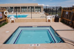 A swimming pool with a black metal fence, lounge chairs, and a lifebuoy. - Quality Inn Taos (Taos)