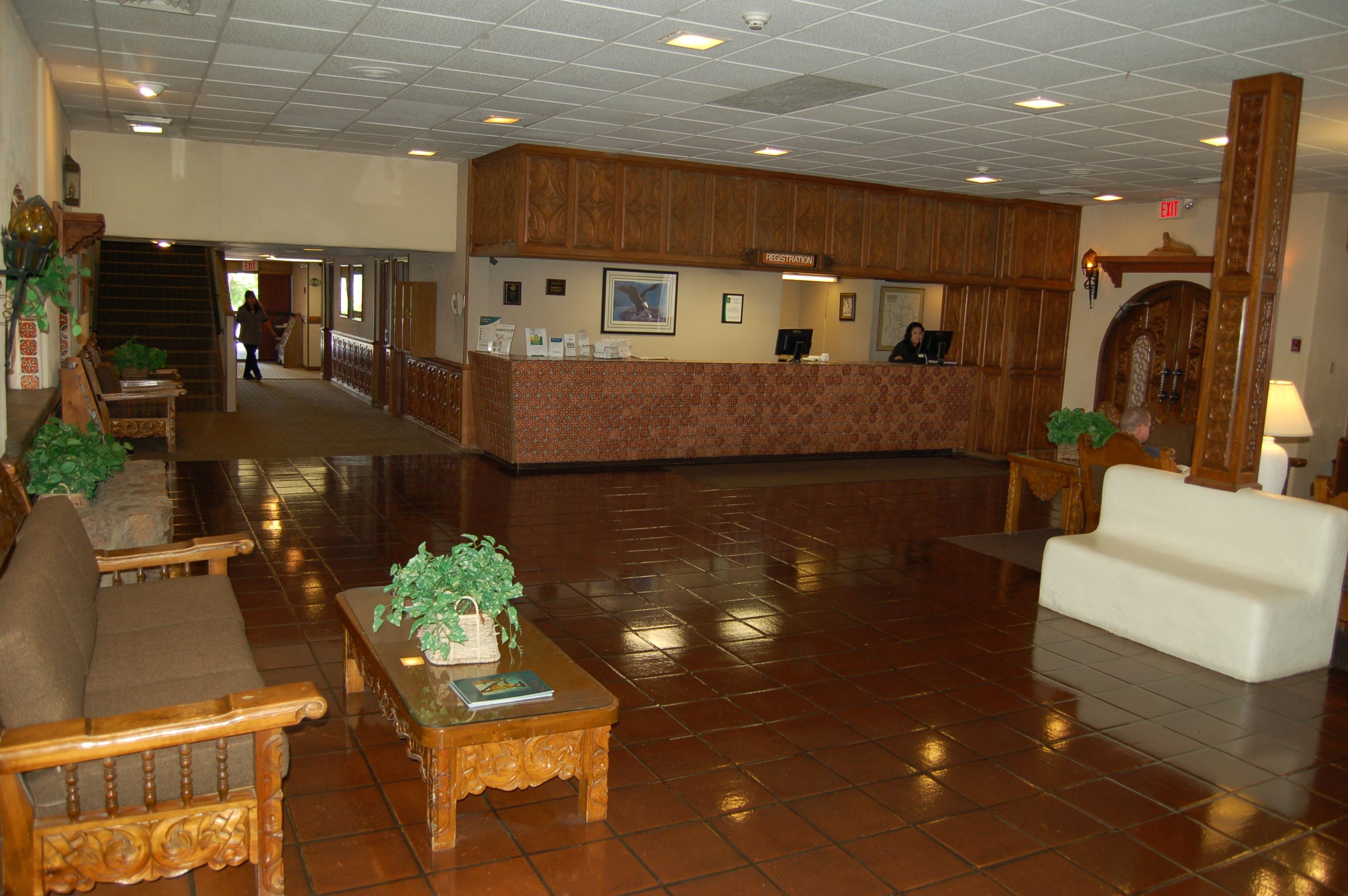 A lobby with a reception desk, wooden furniture, and a tiled floor.