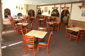 A restaurant with multiple tables and chairs, a patterned carpet, and decorative wall elements. - Quality Inn Taos (Taos)