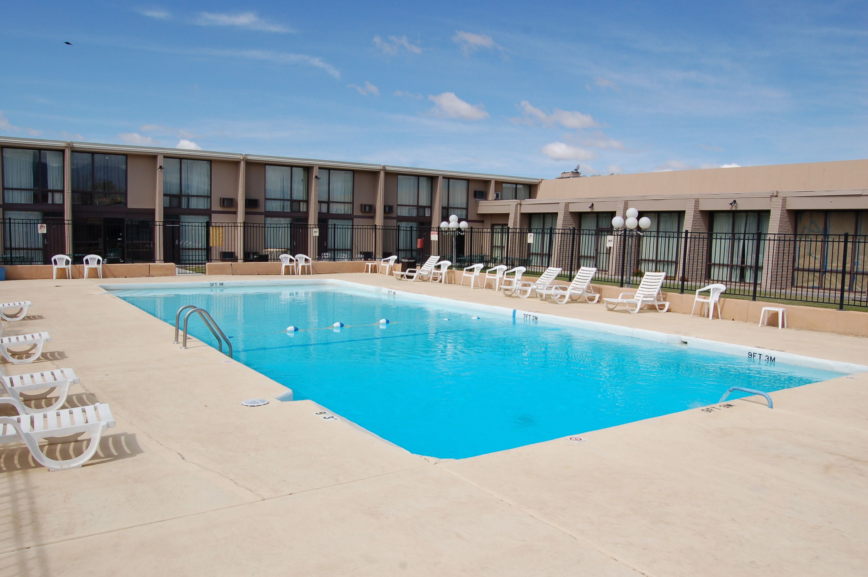 A swimming pool with lounge chairs and a building with multiple windows in the background.