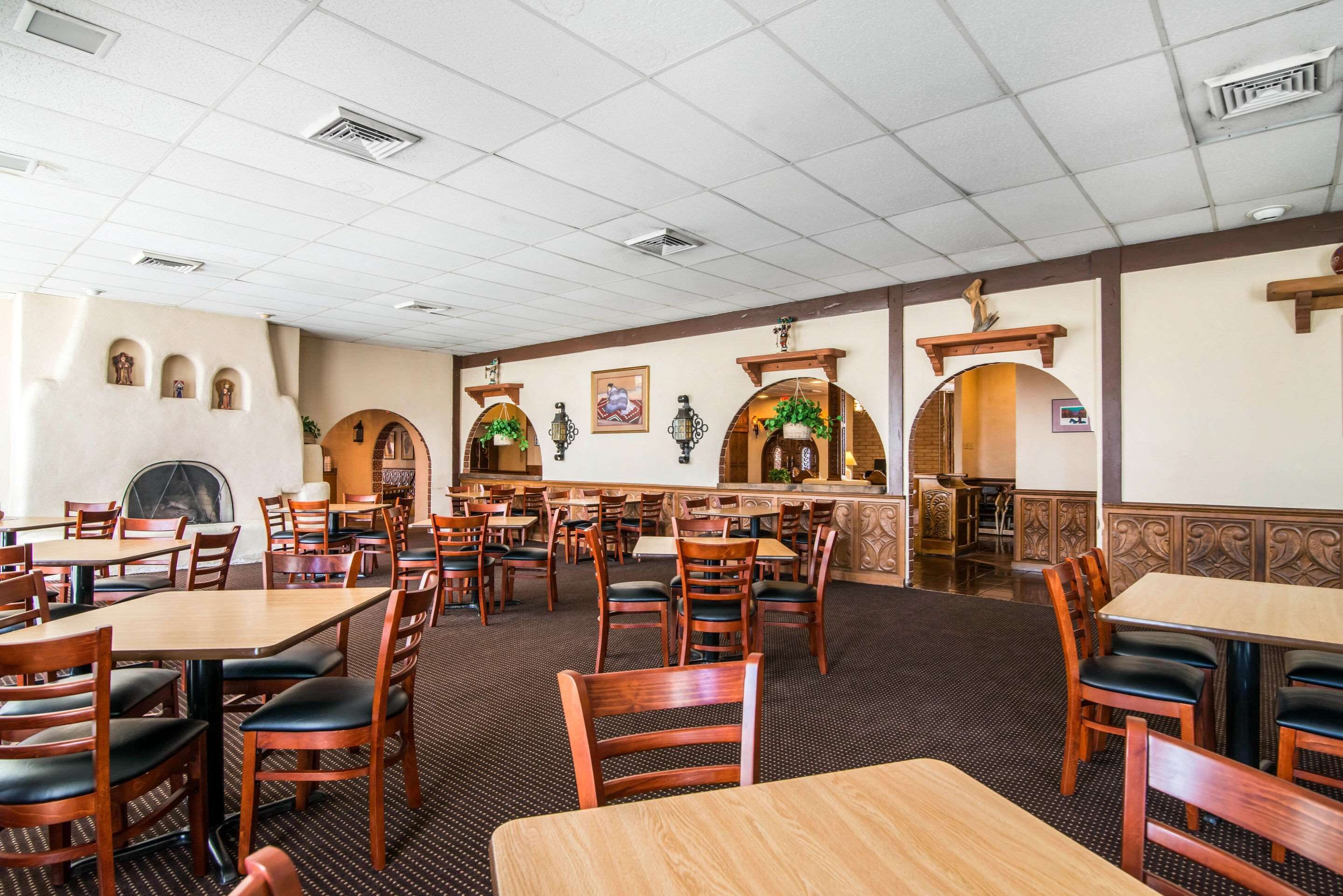 A spacious restaurant with multiple tables and chairs, a bar area, and decorative arches.