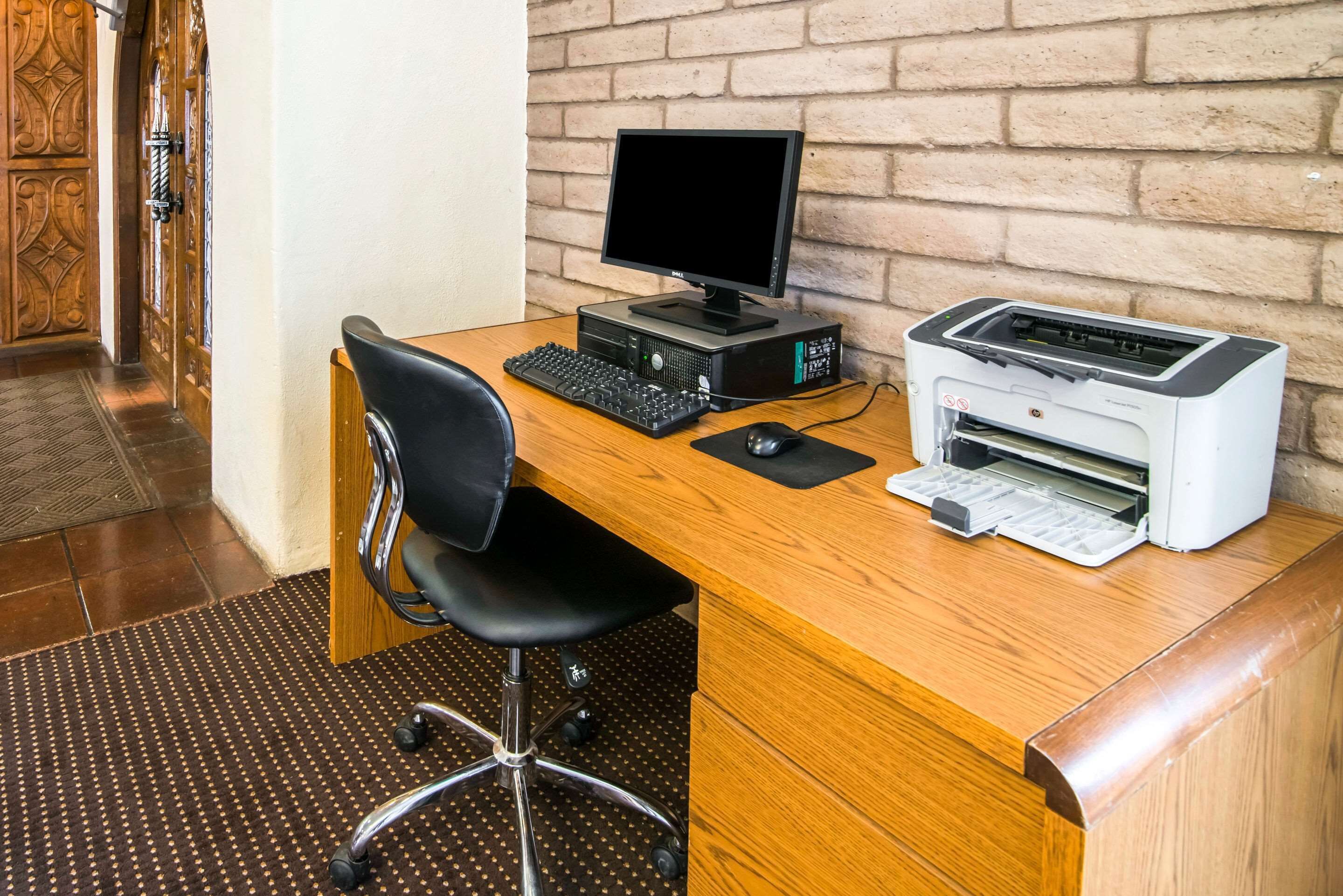 A wooden desk with a computer, keyboard, mouse, and printer.