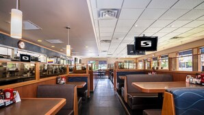 A restaurant interior with booths and tables, a television, and a view of the outside. - Sandman Inn Kamloops (Kamloops)