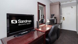 A hotel room with a TV, a desk, a chair, a mirror, and a door. - Sandman Inn Kamloops (Kamloops)
