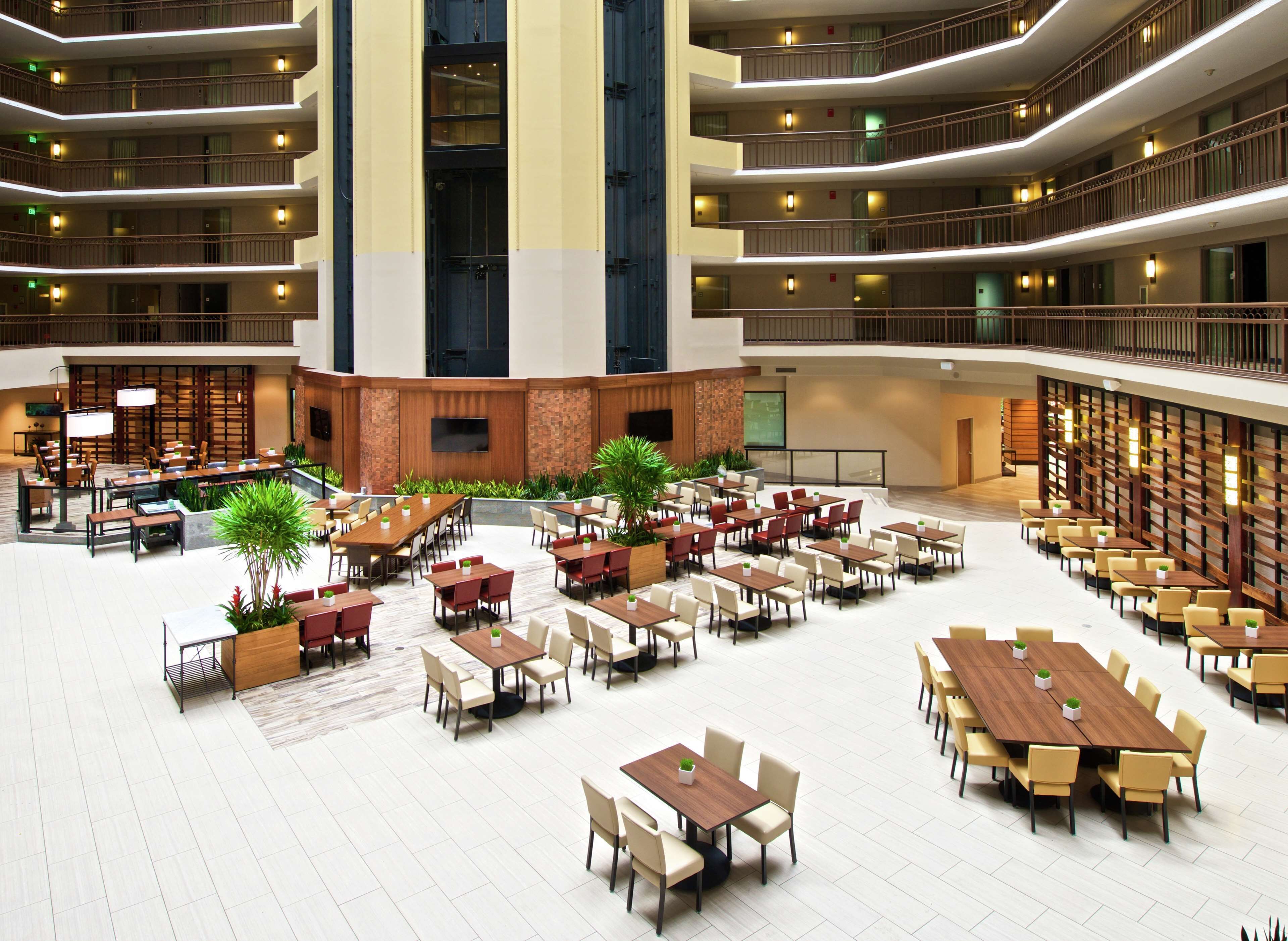A spacious indoor dining area with multiple tables and chairs, a central seating area, and a large screen for presentations.