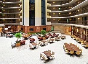 A spacious indoor dining area with multiple tables and chairs, a central seating area, and a large screen for presentations. - Embassy Suites by Hilton Portland Tigard (Tigard)