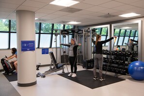 Une salle de sport équipée de matériel d’exercice, de supports pour les poids et d’un grand miroir.