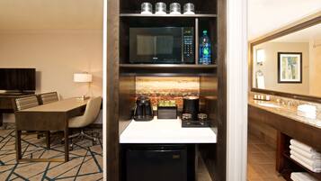 A hotel room with a dining area, kitchenette, and bathroom.