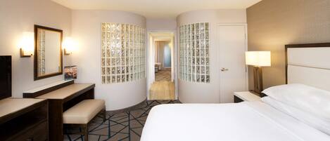 Une chambre d’hôtel avec un lit, un bureau, une chaise, un miroir et une porte.