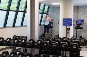 Un gimnasio con equipo de ejercicio, incluyendo cintas de correr y mancuernas.