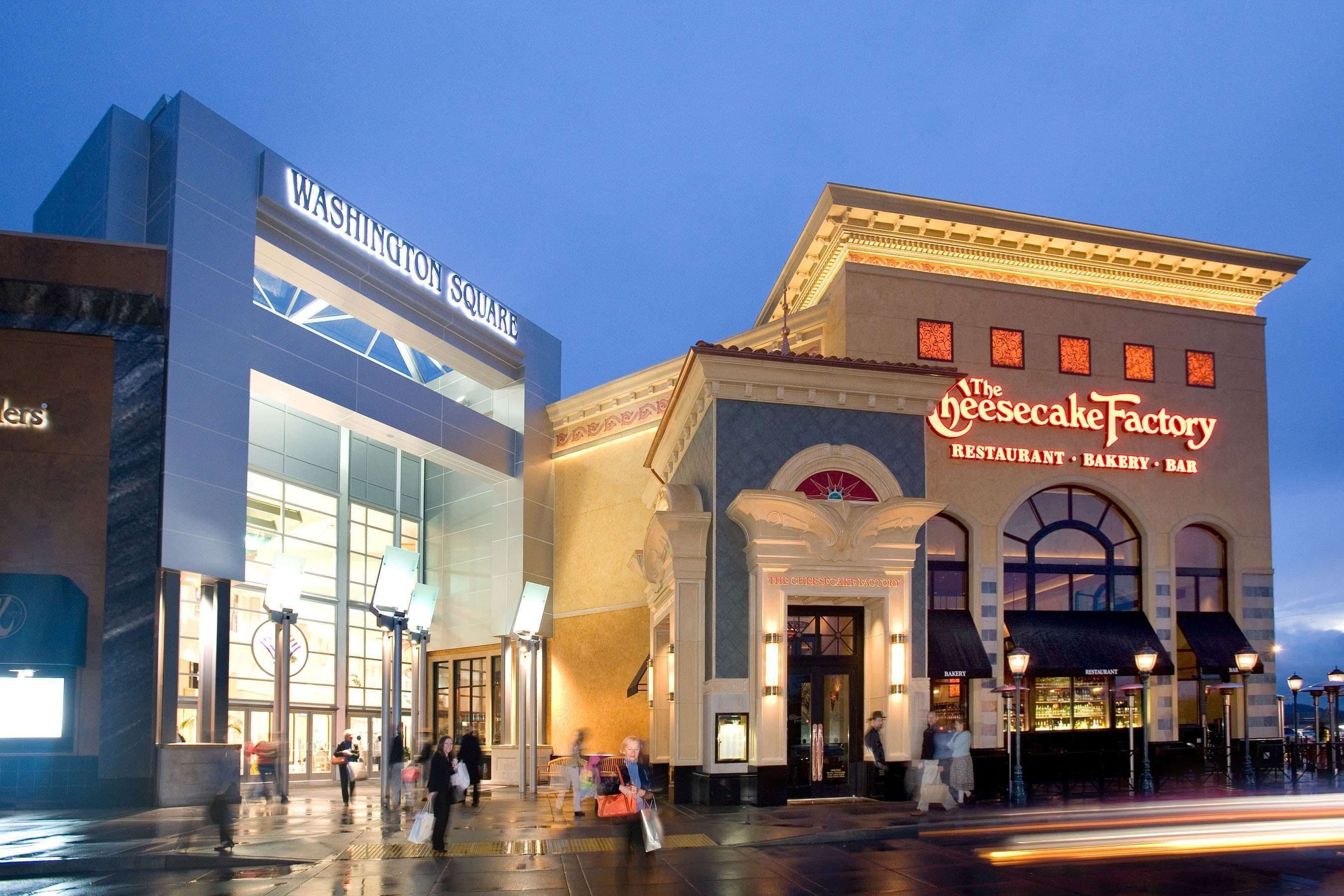 A building with a large sign reading "Washington Square" and another sign for "The Cheesecake Factory."