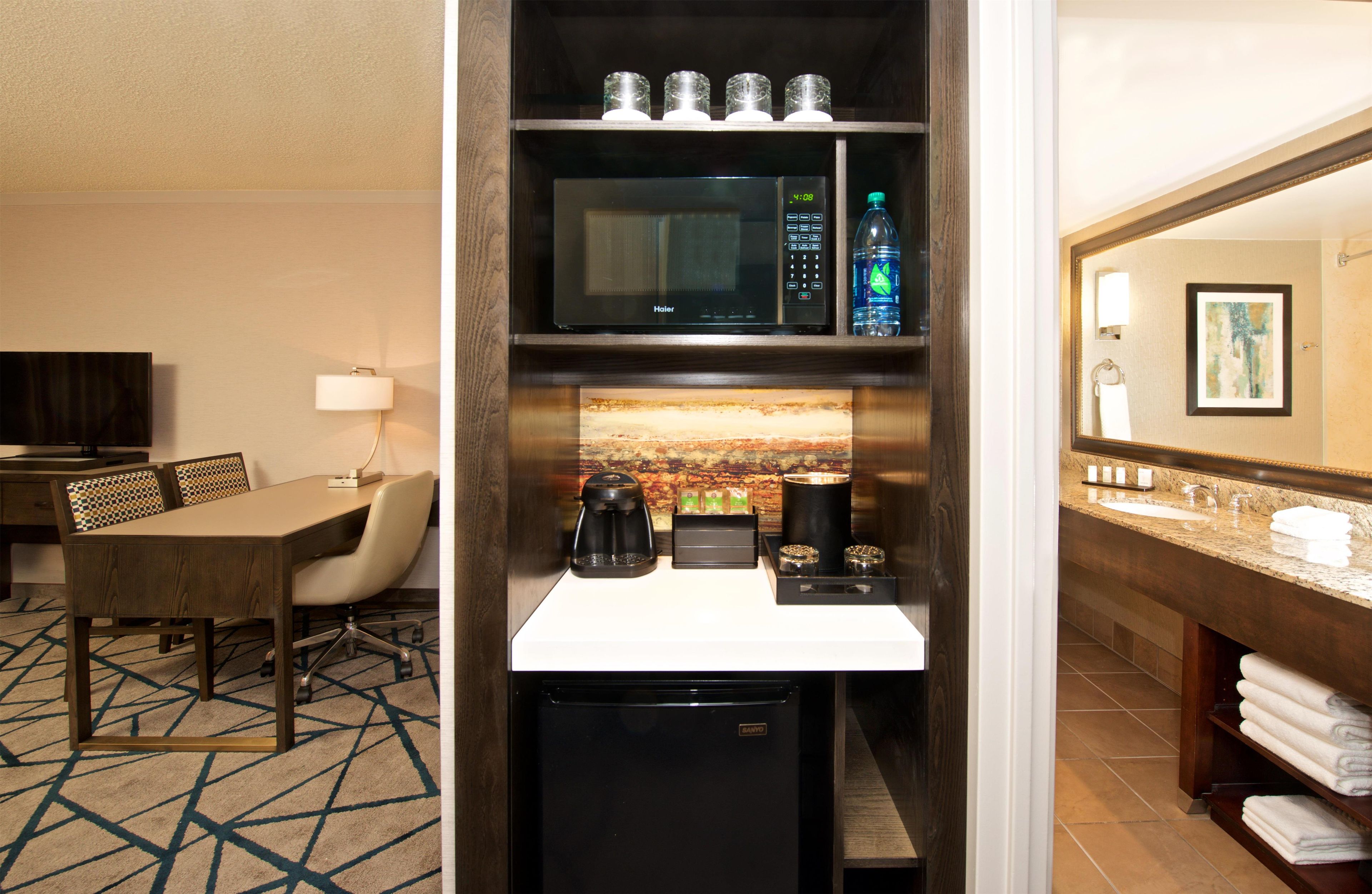 A hotel room with a dining area, a kitchenette, and a bathroom.