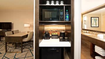 A hotel room with a dining area, a kitchenette, and a bathroom.
