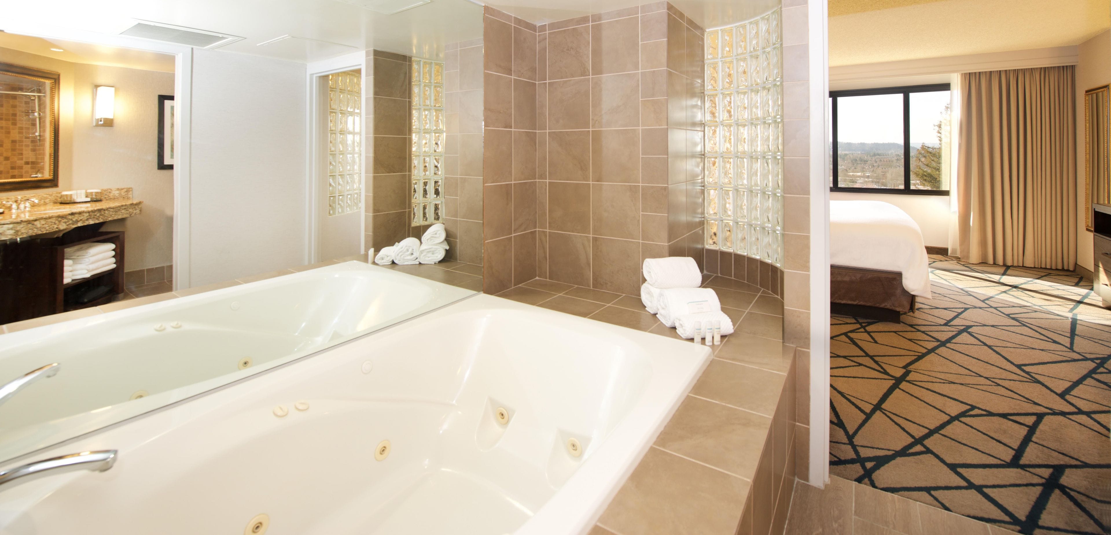 A hotel bathroom with a large bathtub, a shower area, and a toilet.