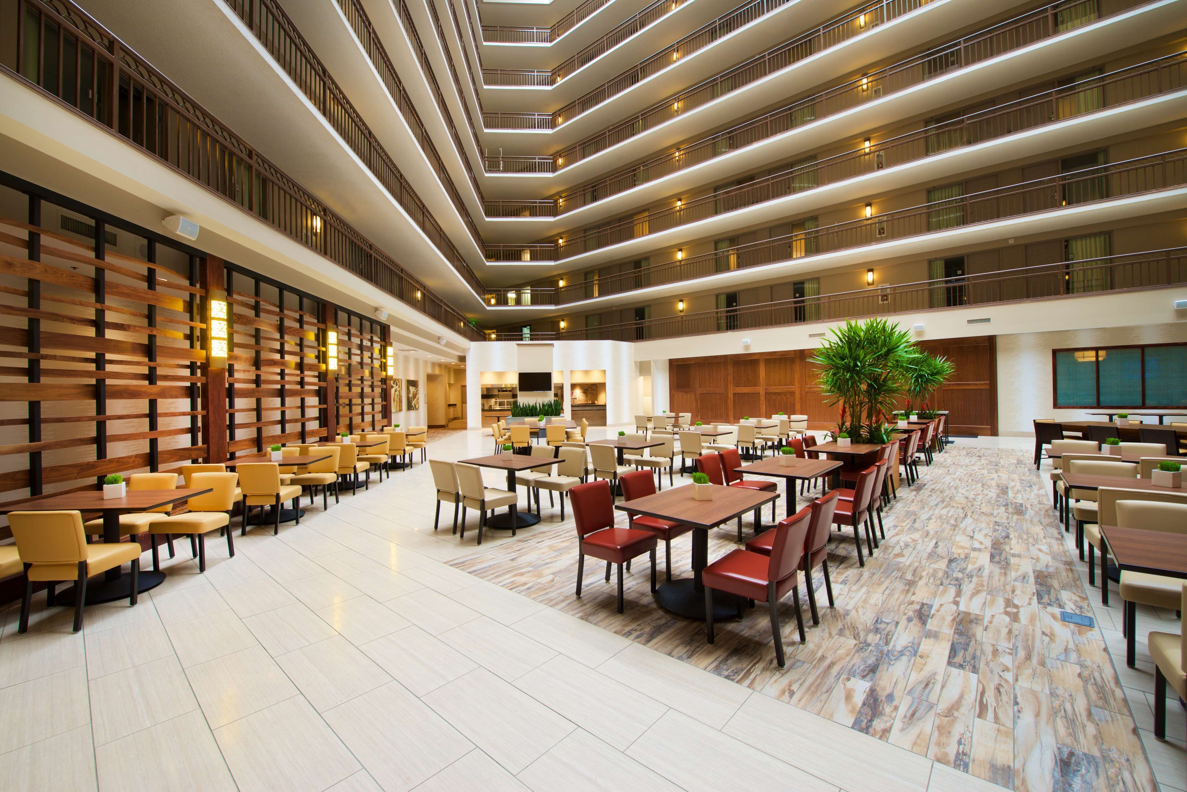 A spacious hotel lobby with multiple dining areas, high ceilings, and a modern design.