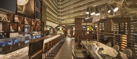 A modern bar area with a long counter, seating, and a unique ceiling design.