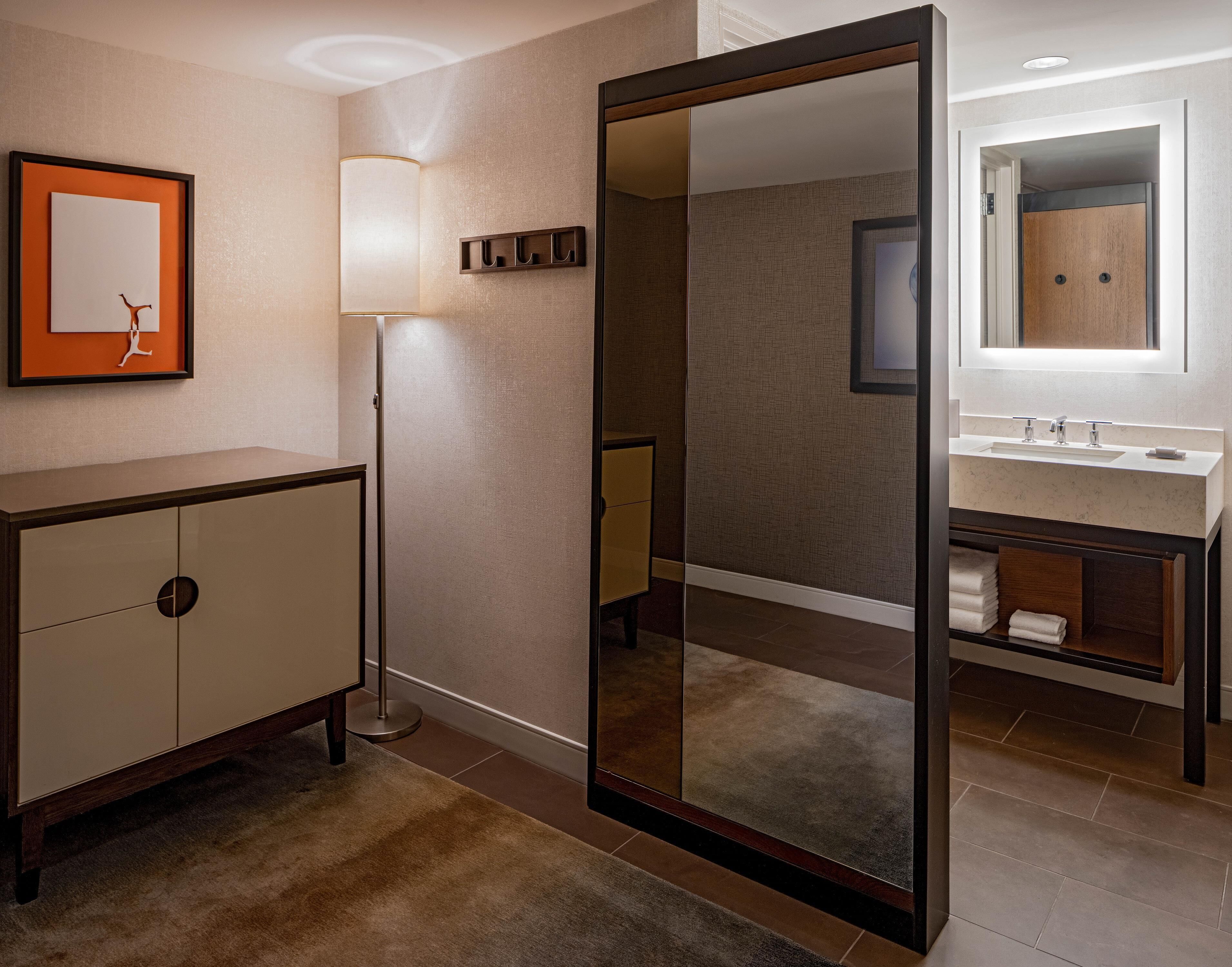 A modern bathroom with a large mirror, a vanity with a sink, and a cabinet.