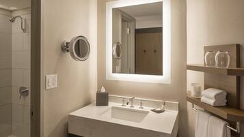 A modern bathroom with a large mirror, a sink, and a shower.