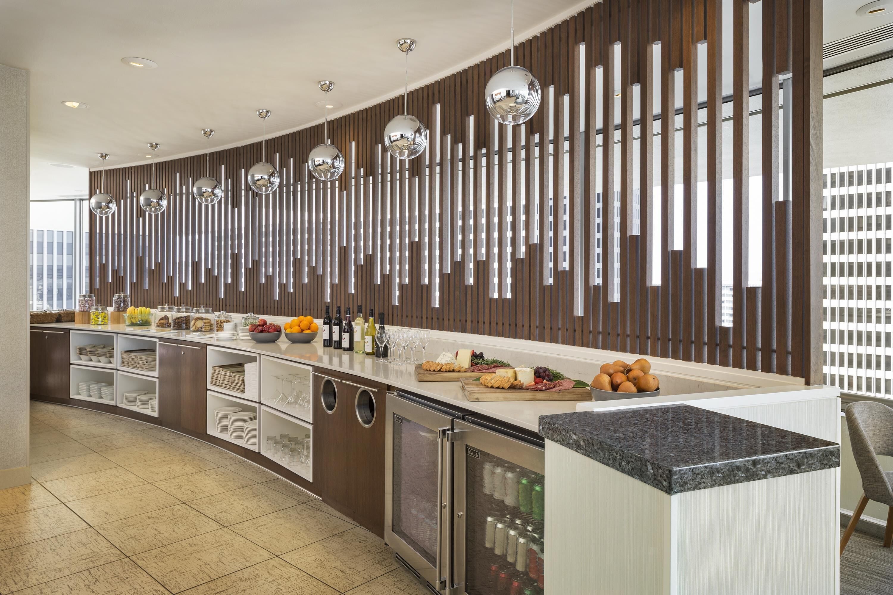 A modern kitchen with a long counter, stainless steel appliances, and a decorative wall with vertical elements.