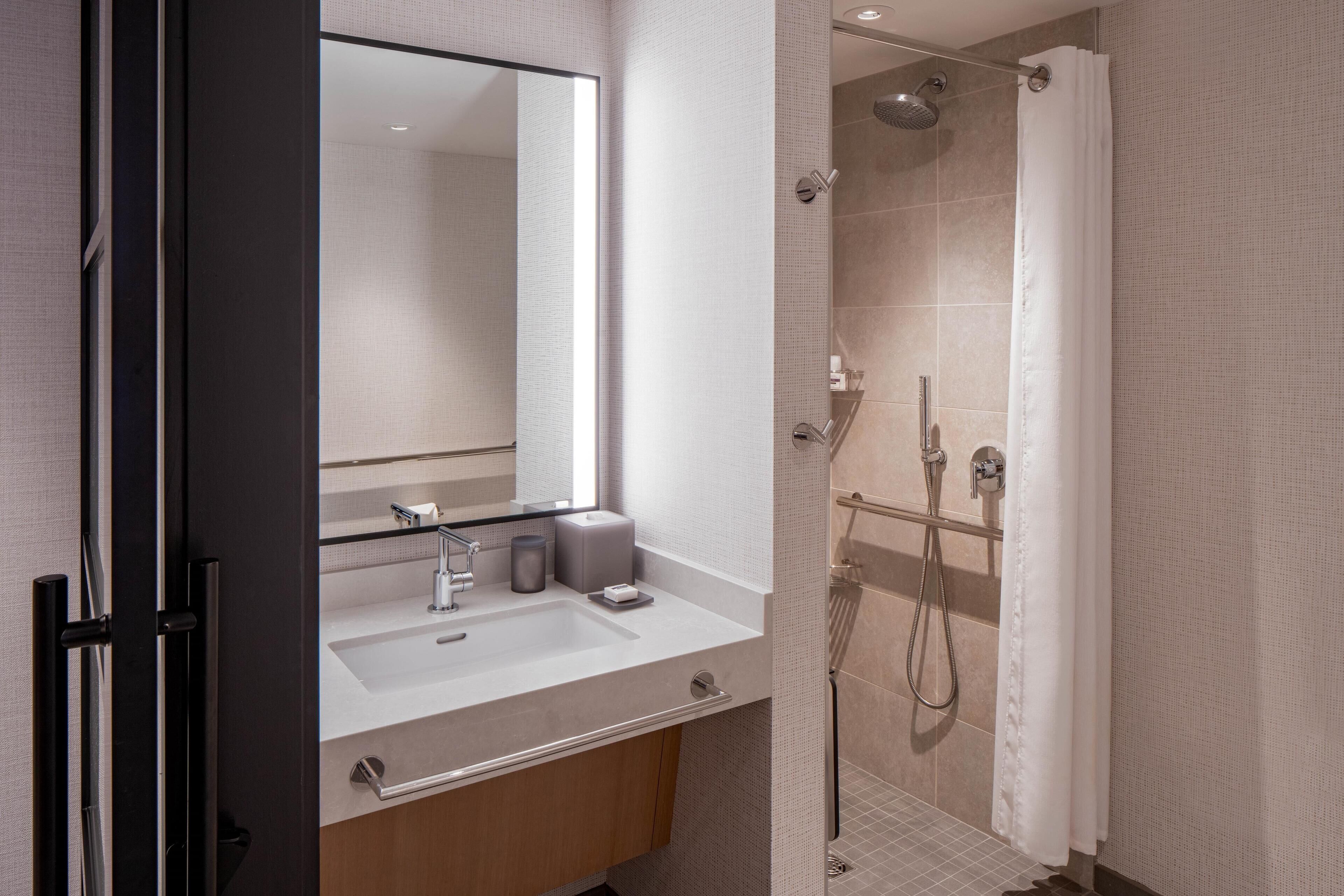 Een moderne badkamer met een wastafel, spiegel en douche.