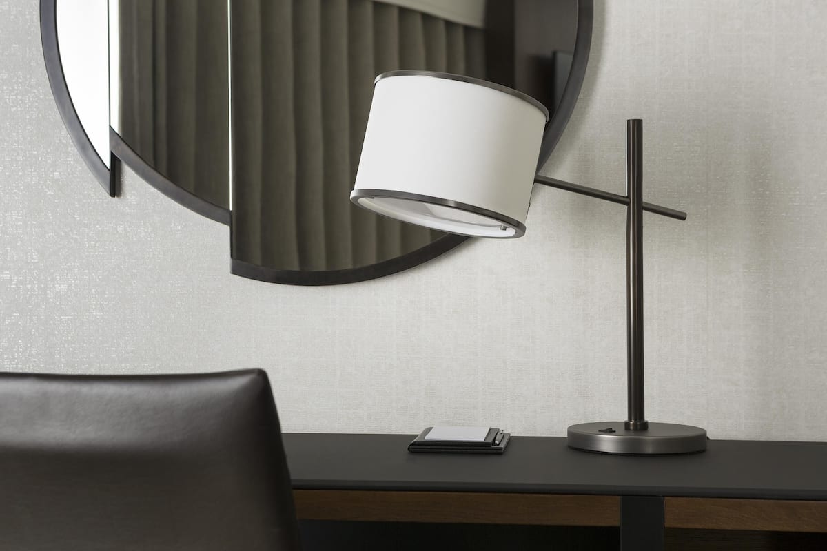 Una scrivania moderna con una lampada, un quaderno e uno smartphone.
