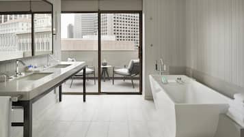 A modern bathroom with a large bathtub, a double sink, and a seating area with chairs.