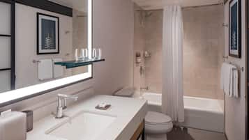 A modern bathroom with a large mirror, a sink, a toilet, a shower, and a bathtub.