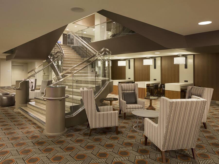 A hotel lobby with a staircase, seating area, and a reception desk.