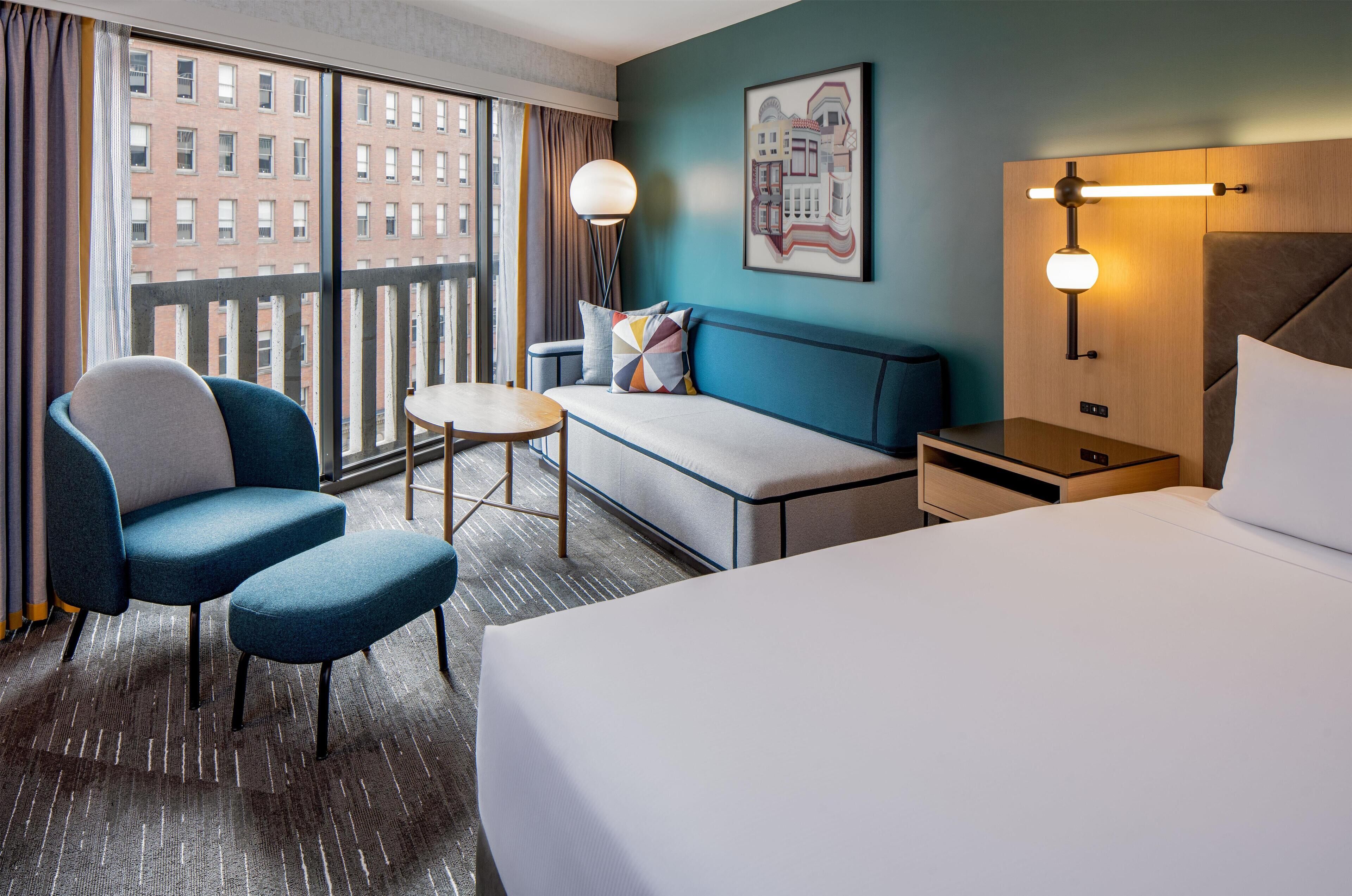 Une chambre d’hôtel avec un grand lit, un canapé, une chaise, une petite table et une table de chevet.