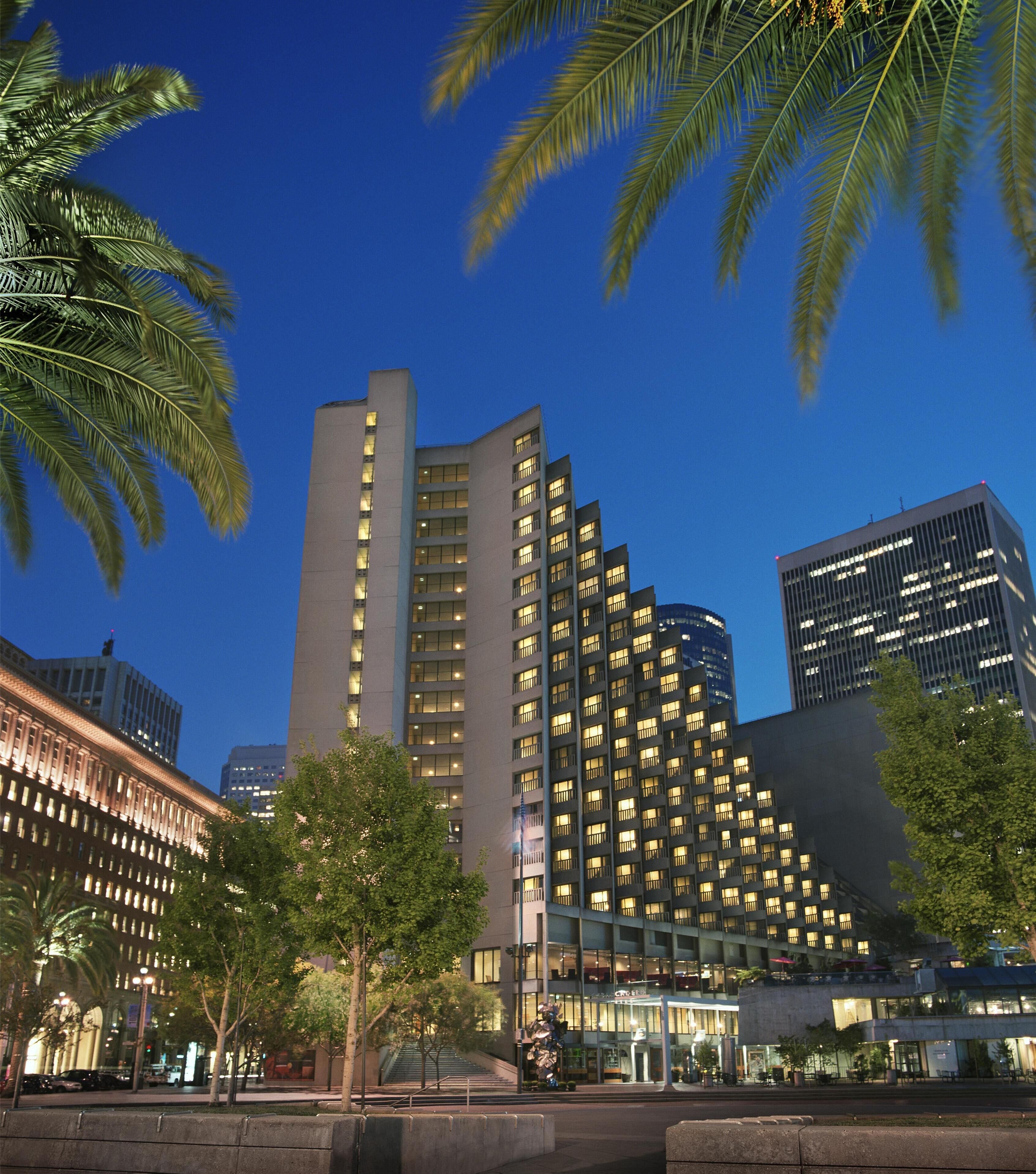 A modern hotel with multiple floors, large windows, and a well-lit facade.