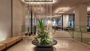 A modern lobby with a central floral arrangement, seating area, and a staircase leading to upper floors. - Grand Hyatt Melbourne (Melbourne)