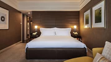 Una habitación de hotel con una cama grande, una mesita de noche, una silla y cuadros en las paredes.