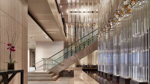 A modern lobby with a marble floor, a glass staircase, and decorative vertical elements. - Grand Hyatt Melbourne (Melbourne)