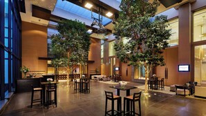 A spacious indoor area with multiple seating arrangements, including tables and chairs, and large windows allowing natural light. - Grand Hyatt Melbourne (Melbourne)