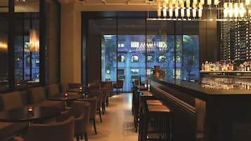 Una zona de bar con asientos y una estantería para vinos.