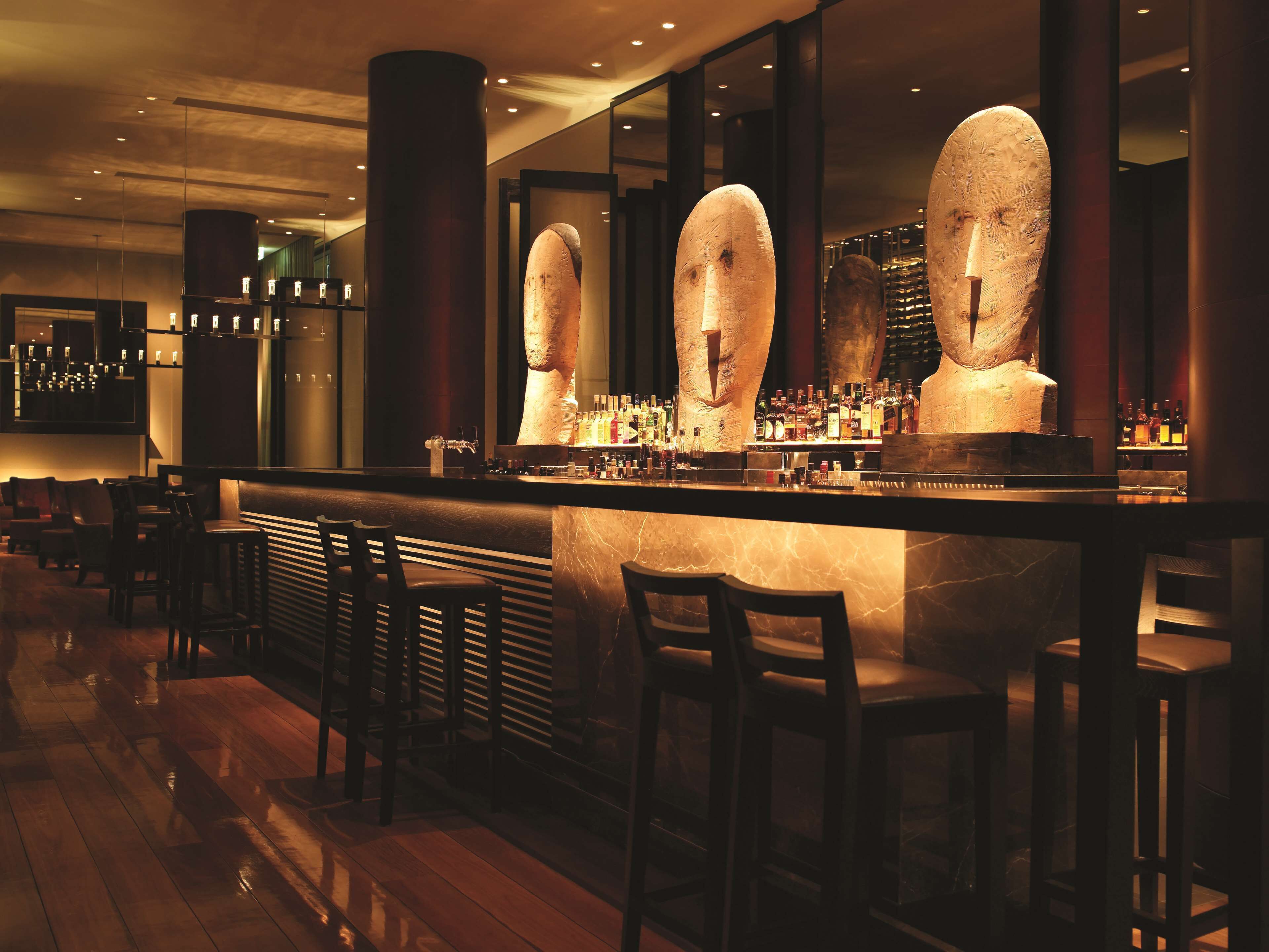 A bar area with a marble countertop, multiple liquor bottles, and bar stools.