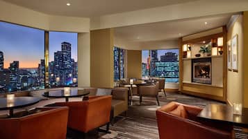A modern hotel room with a city view, a fireplace, and comfortable seating.