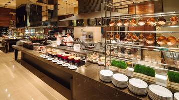 A modern kitchen with stainless steel appliances, a buffet counter with various dishes, and copper cookware hanging on the wall.
