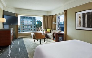 A hotel room with a large bed, a desk with a chair, a sofa, a TV, and a window with a city view. - Grand Hyatt Melbourne (Melbourne)