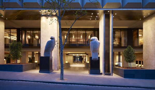 A modern hotel entrance with two large stone sculptures, a covered walkway, and a glass facade. - Grand Hyatt Melbourne (Melbourne)